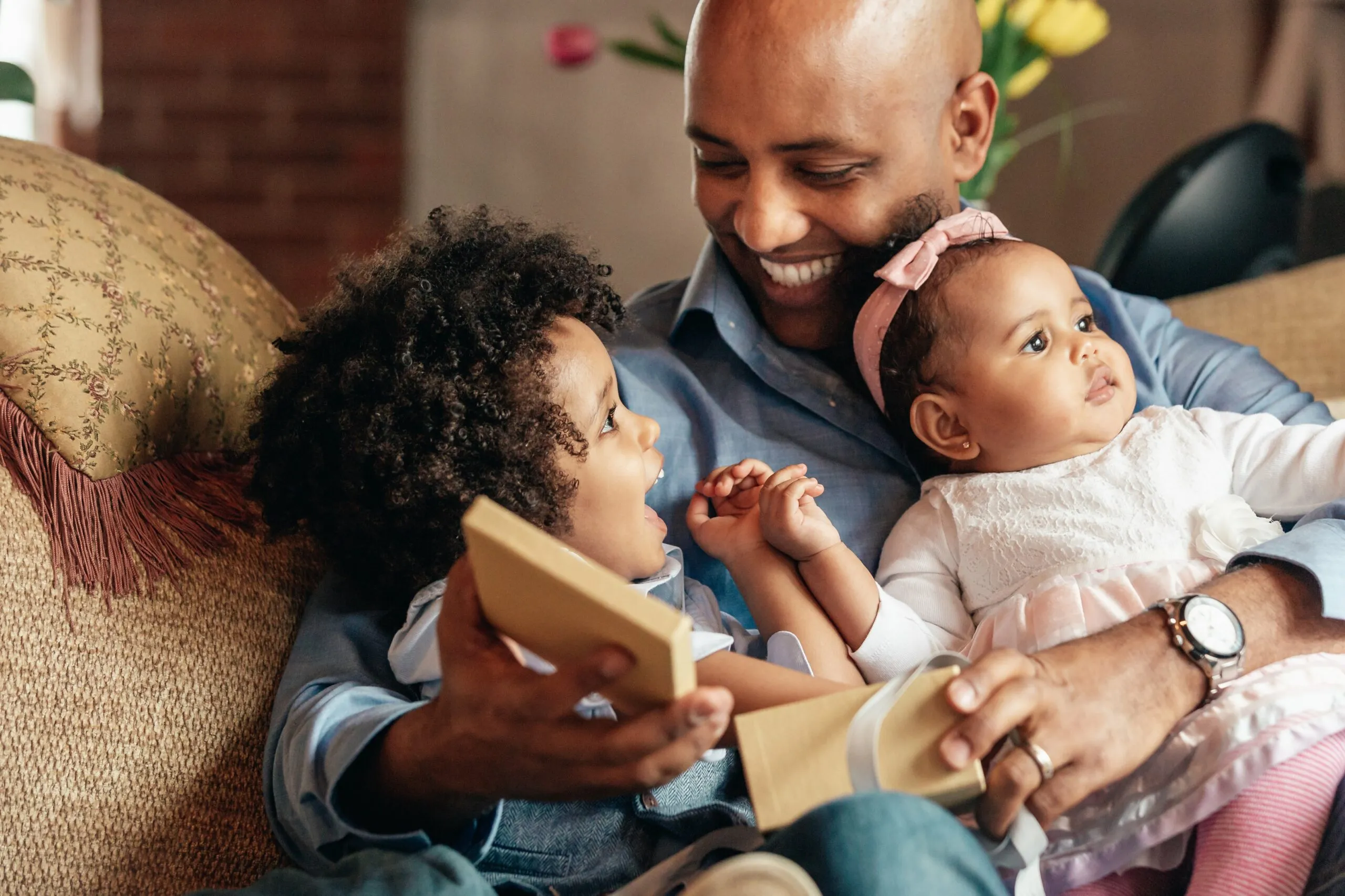 young boy smiles at father holding baby sister scaled